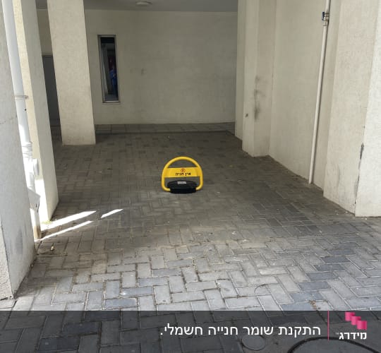מחסום חניה צהוב על רצפת אבנים משתלבות